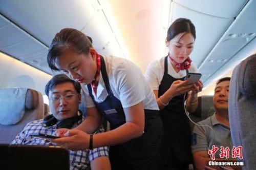 資料圖：乘務(wù)員們在客艙內(nèi)為旅客調(diào)試機(jī)上上網(wǎng)功能。<a target='_blank' ><p  align=