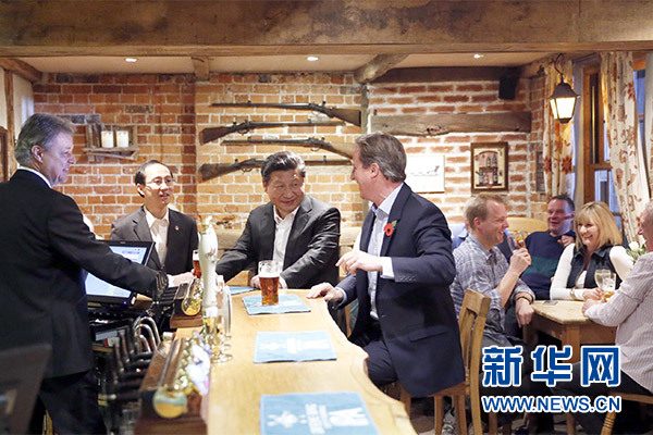 這是會晤結(jié)束后，習近平在卡梅倫陪同下乘車前往當?shù)匦℃?zhèn)體驗酒吧文化。新華社記者 鞠鵬 攝